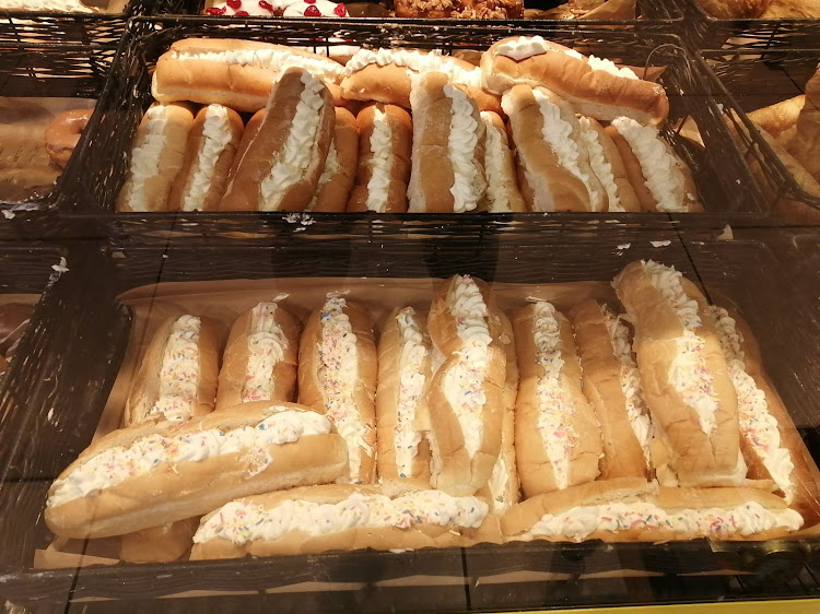 Hot dog rolls with a sweet dessert topping, as sold at a supermarket bakery.