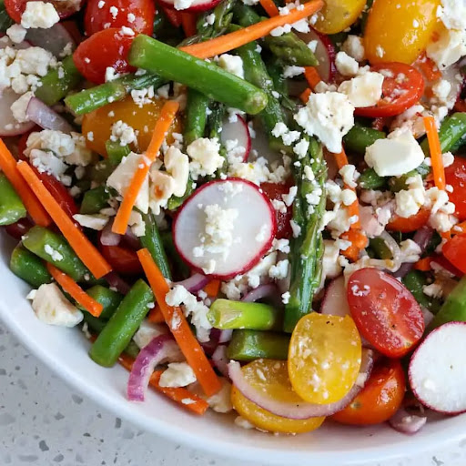 A fresh spring asparagus salad recipe with cherry tomatoes, radishes, carrots, and red onion all tossed in a fresh lemon Dijon mustard vinaigrette and sprinkled with crumbled feta cheese. 