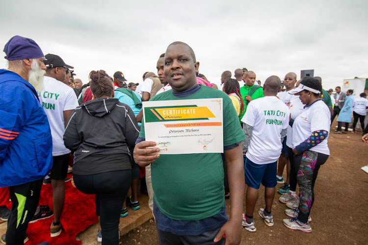 Peter Mcharo displays his Certificate of Participation after the run.