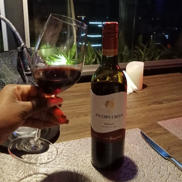 A glass of wine and bottle displayed in a restaurant during a solo date.