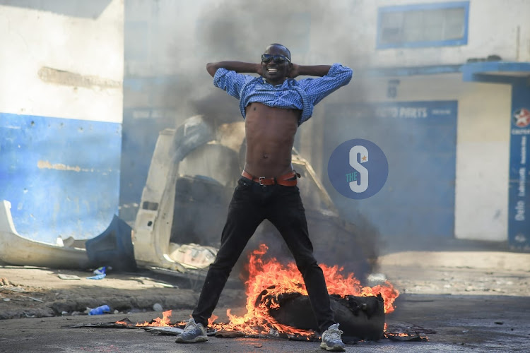 A protester stands next to a bonfire during anti government protests in Mombasa county on July 19, 2023