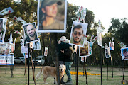  A couple hug near photos of victims killed during Hamas' October 7 attack on civilians attending the Nova music festival in Israel. Israel has accused South Africa of siding with Hamas in its repeated petitions to the International Court of Justice.