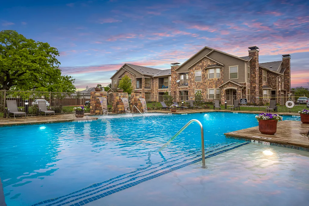 Mansions at Hickory Creek's resort-style swimming pool with waterfall feature at dusk