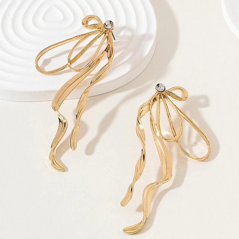 Boucles d'oreilles nœud large irrégulières pour femmes avec pompons et streamers – accessoire tendance pour un look féminin et sophistiqué.