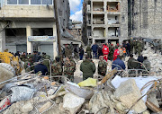 Russian military police and Syrian army and police members stand at the site of damaged buildings, as the search for survivors continues, in the aftermath of the earthquake, in Aleppo, Syria.