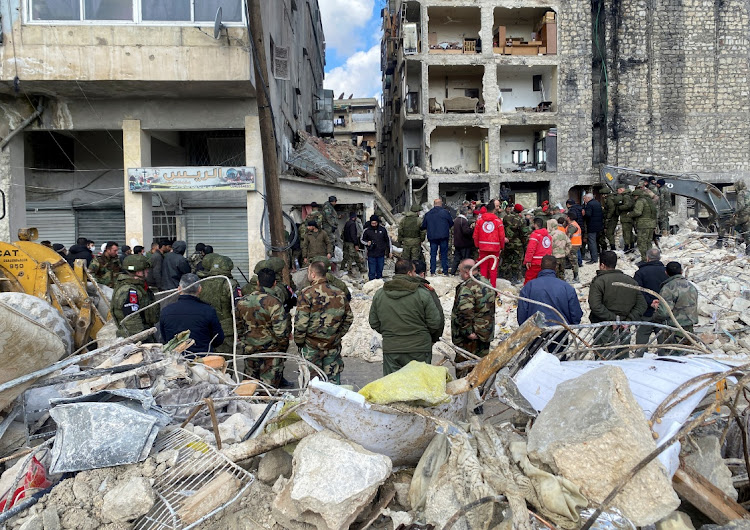 Russian military police and Syrian army and police members stand at the site of damaged buildings, as the search for survivors continues, in the aftermath of the earthquake, in Aleppo, Syria.