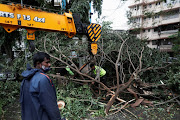 People attempt to remove uprooted trees from the entrance of a residential building after strong winds caused by Cyclone Tauktae, in Mumbai, India, May 18, 2021. 