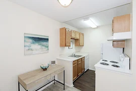 Kitchen with wood-inspired flooring, white appliances, and wood cabinets