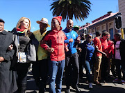 Opposition leaders including EFF's Julius Malema and DA's Mmusi Maimane lock arms as they march to the Constitutional Court where the secret ballot hearing is taking place on 15 May 2017.