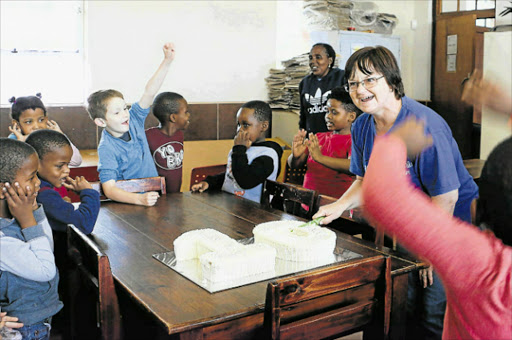 VITAL SERVICE: Founder and director of Autism Sinethemba Antoinette Bruce-Alexander cuts the cake as staff members and pupils cheer in celebration of the school's 10th birthday Picture: MADELEINE CHAPUT