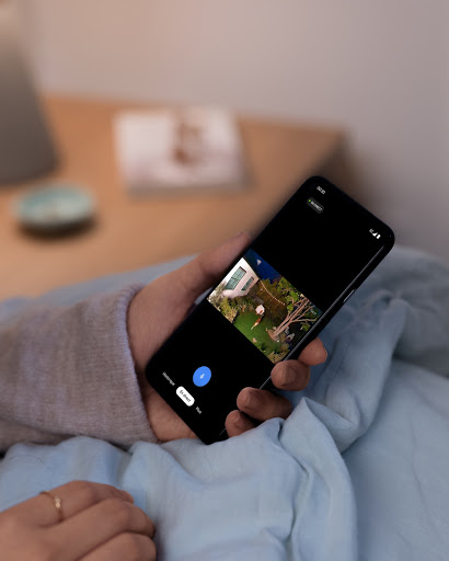 À l'intérieur de chez elle, une personne assise consulte son téléphone.