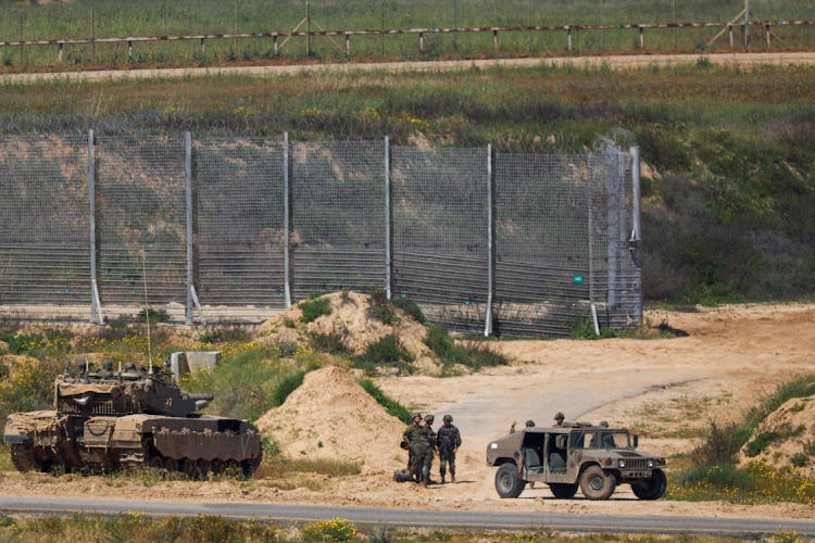 Israeli soldiers stand near military vehicles, amid the ongoing conflict between Israel and the Palestinian Islamist group Hamas, near the Israel-Gaza border, as seen from Israel, April 4, 2024.