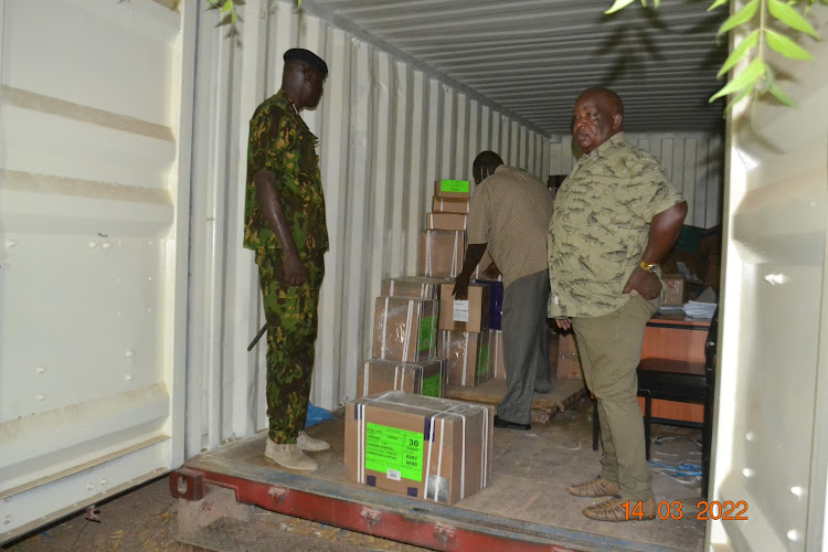 Turkana police commander samuel Ndanyi and county commissioner Wambua Muthama inspect the opening of exam materials ina container in Lodwaron Monday.