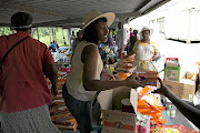 Princess Ngcobo passes around  groceries as her fellow stokvel members receive their share  in the parking lot at a store in Durban. / Rogan Ward