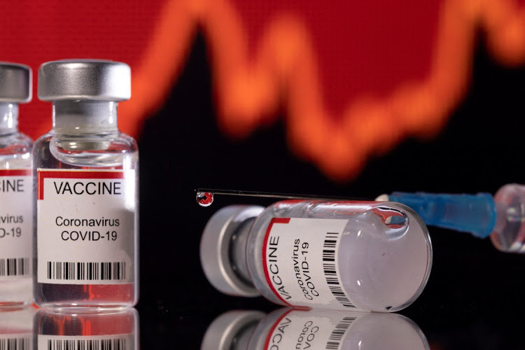 Vials labelled "VACCINE Coronavirus Covid-19" and a syringe are seen in front of a displayed graph in this illustration taken December 11, 2021.