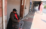 Security guard Gudda Ngubane sits guard with a sjambok in the Johannesburg CBD. Due to threats from the national shutdown many businesses have closed their doors for the day.