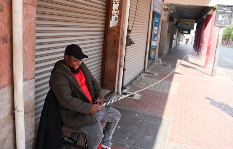 Security guard Gudda Ngubane sits guard with a sjambok in the Johannesburg CBD. Due to threats from the national shutdown many businesses have closed their doors for the day.