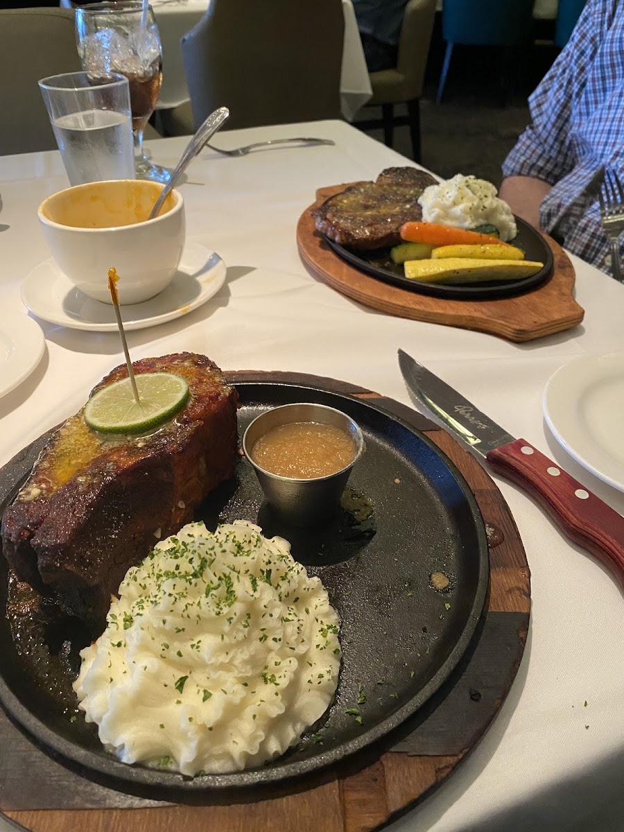 Lunch portion of the Perry's porkchop. Gluten-free lobster bisque and gluten-free steak in the background.