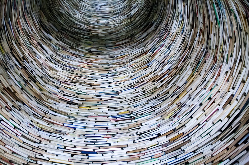 Many different books stacked on top of each other, forming a funnel-like shape.