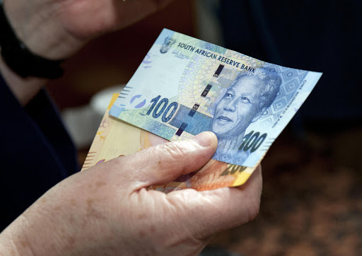 Reserve Bank Governor Gill Marcus shows off the new banknotes, which feature an image of former president Nelson Mandela on the front and images of the "Big Five" wild animals on the reverse, before conducting the first transaction in on November 6, 2012 in Pretoria, South Africa.