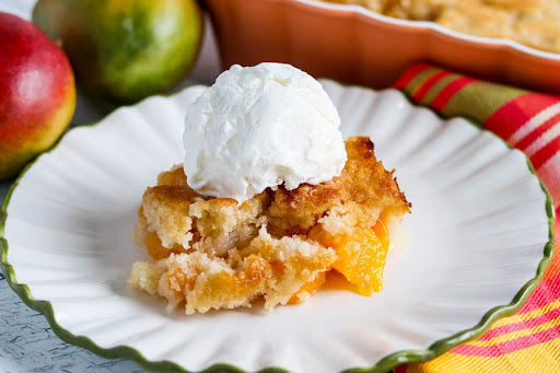 A slice of Mango Cobbler with vanilla ice cream on a plate.