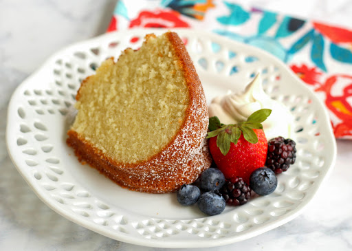 A slice of pound cake on a plate with berries.