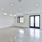 Polished concrete flooring in downstairs living space with walkout basement door and window looking out to the backyard