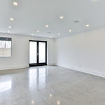 Polished concrete flooring in downstairs living space with walkout basement door and window looking out to the backyard