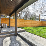 Back view of modern house patio with stone interlock and landscaping
