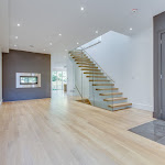 Dining room with modern staircase, two-sided fireplace, and white oak flooring