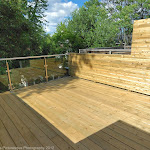 Newly installed wooden patio with privacy wall and glass railings