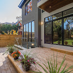 Back view of house with wood patio, stone interlocking, and a walk-out basement with glass railing