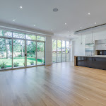 Modern kitchen and living area with large windows looking out to the backyard