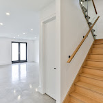 White oak hardwood stairs leading into the basement with polished concrete flooring and glass railings