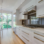 Modern kitchen with gray high glass backsplash and white cabinetry