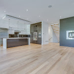 Modern kitchen and living area with two sided fireplace and white oak hardwood flooring