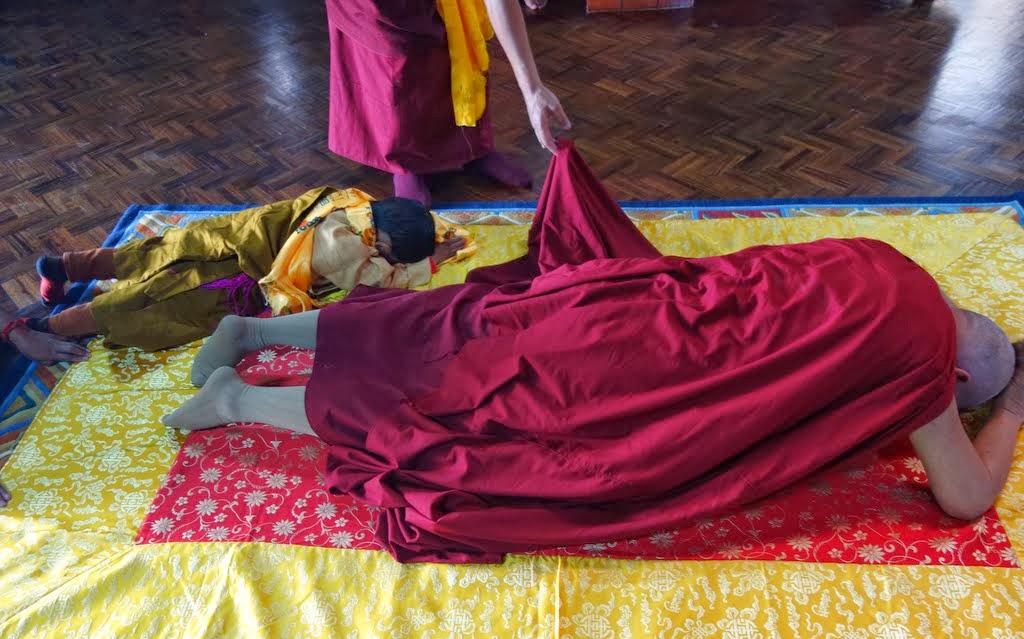 After doing prostrations, Lama Zopa Rinpoche offers khatas to a photo of His Holiness the Dalai Lama and the holy objects in the nunnery's gompa, Khachoe Ghakyil Nunnery, Nepal, November 22, 2013. Photo by Ven. Roger Kunsang.