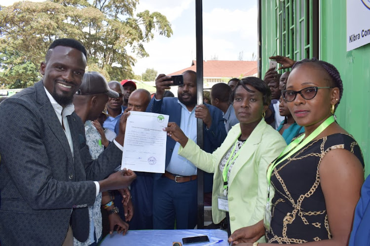 Jubilee aspirant for the upcoming Kibra by-election MacDonald Mariga being issued with the nomination certificate by IEBC Returning Officer in Kibra Beatrice Muli on September 16, 2019.