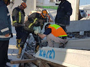 Rescue technicians use specialized equipment in their effort to recover the bodies of three men killed when a building collapsed in Jacobs, Durban, on Wednesday. 