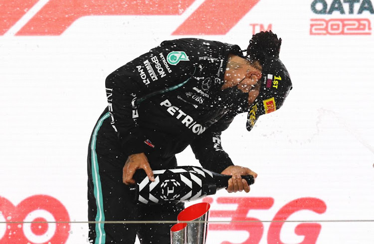 Race winner Lewis Hamilton of Great Britain and Mercedes celebrates on the podium during the Formula One Grand Prix of Qatar at Losail International Circuit on November 21 2021 in Doha.