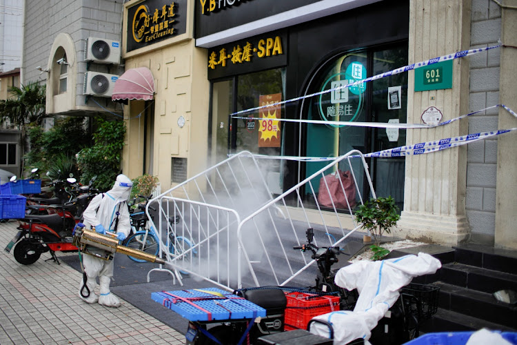 A worker in a protective suit disinfects a street during lockdown, amid the Covid-19 outbreak, in Shanghai, China, on May 20 2022. Picture: REUTERS/ALY SONG