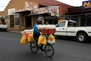 A man cycles in the cold weather as he balances a heavy load of shopping bags and crates in Brakpan, Gauteng on June 17 2020.