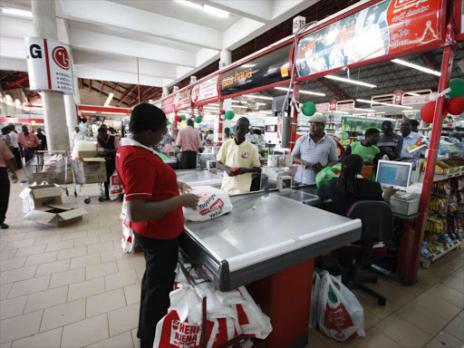 A supermarket attendant at the till prepares to put customer’s goods in a polythene bag /FILE