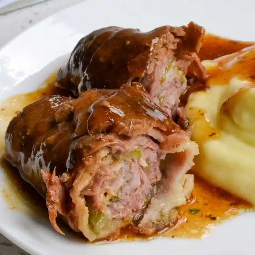 German Beef Rouladen are rolls of thin, tender round steak stuffed with spicy mustard, bacon, onions, and pickles, all baked to fork tenderness.  Then it is smothered with an easy-to-make beef sauce made from the delicious browned bits and beef juices.