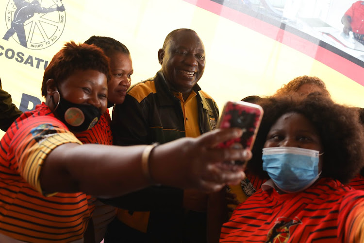 Domestic workers and members of Cosatu take selfies with President Cyril Ramaphosa in October 2021 at a Cosatu event in Ekurhuleni. Relations between the union federation and the president have cooled over the past few years.