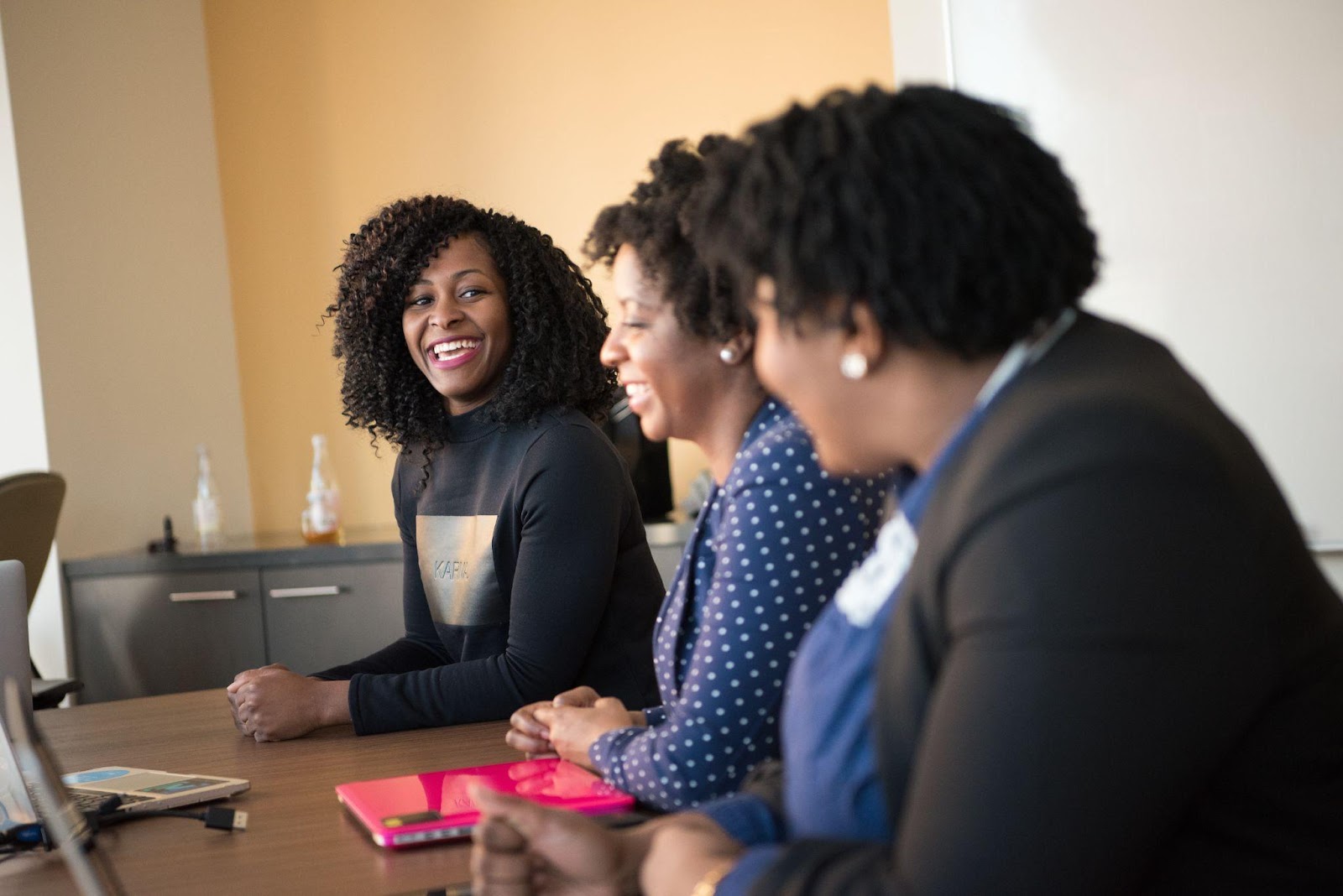 Three People Smiling and Sitting at a Desk