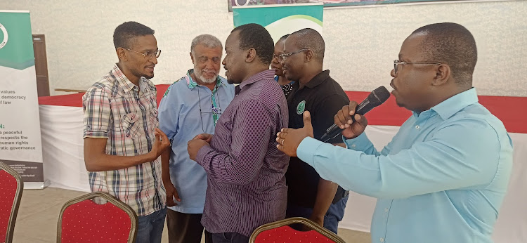 Mombasa county engineer in the housing department Abdulaziz Kassim [L] complains after being heckled by angry residents at the Tudor Pastoral Centre on Tuesday.