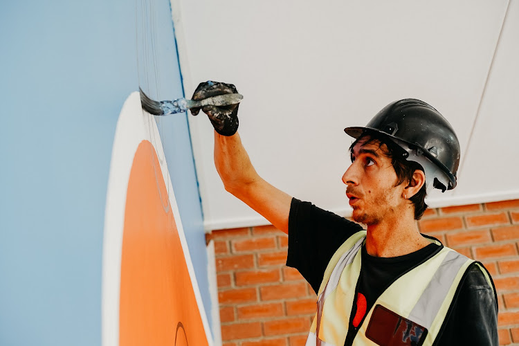 A painter works on one of the murals on the school grounds.