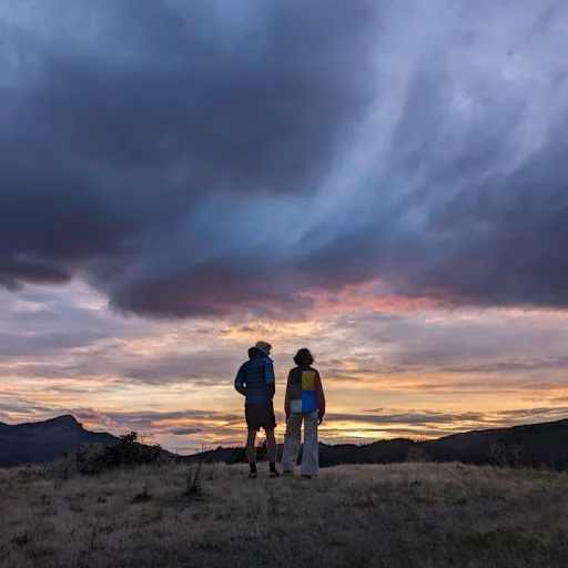 Two people looking at a sunset from a vista