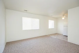 Living room looking into dining room featuring neutral carpet, white walls and trim, windows with blinds, ceiling fan 